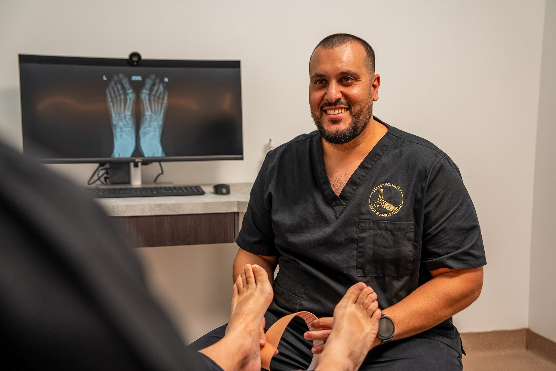 Bexley Podiatry podiatrist treating a patient with diagnostic foot X-rays displayed