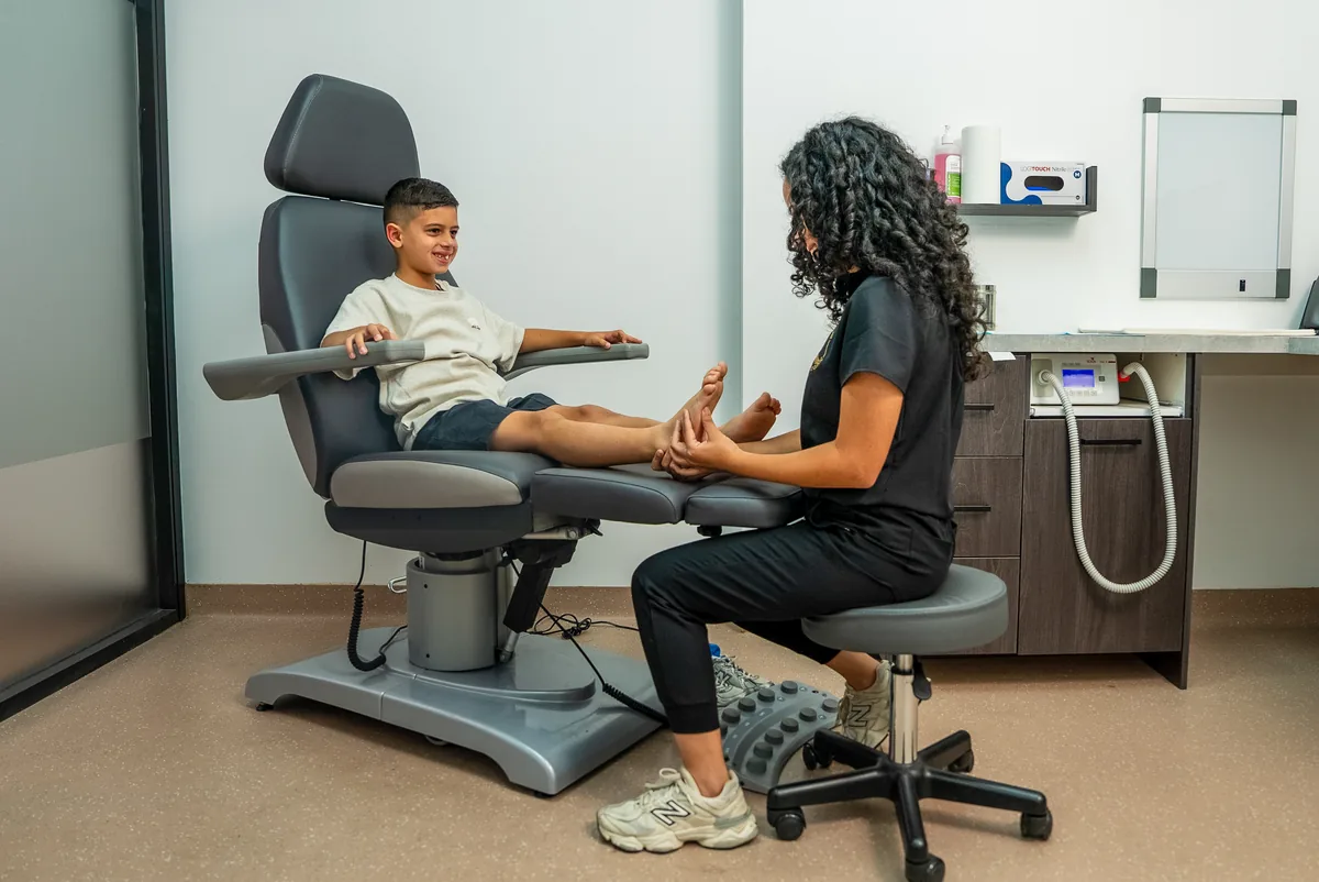 A podiatrist assessing how a child stands and moves in the Bexley clinic