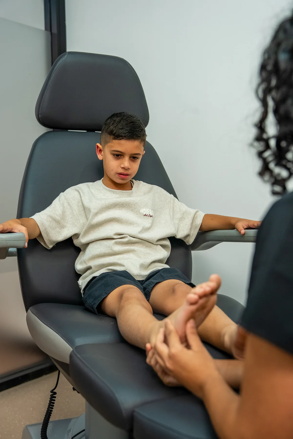 A young patient having their foot examined in the treatment chair at Bexley Podiatry